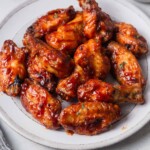 air fryer bbq chicken wings on a plate with bbq sauce.