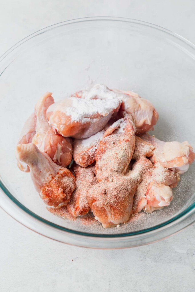 chicken wings in a bowl with seasoning.
