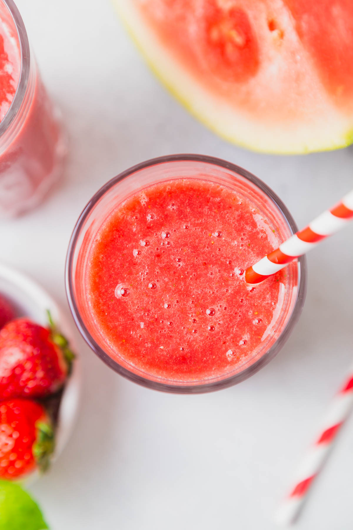 strawberry watermelon smoothie in a glass with a straw.