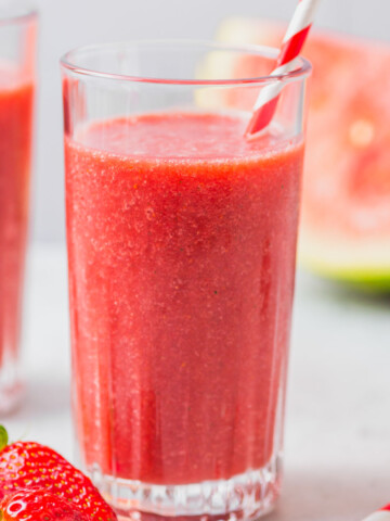 watermelon smoothie with strawberries with a red straw.