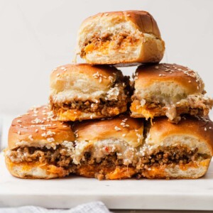 ground beef sliders stacked on a board.