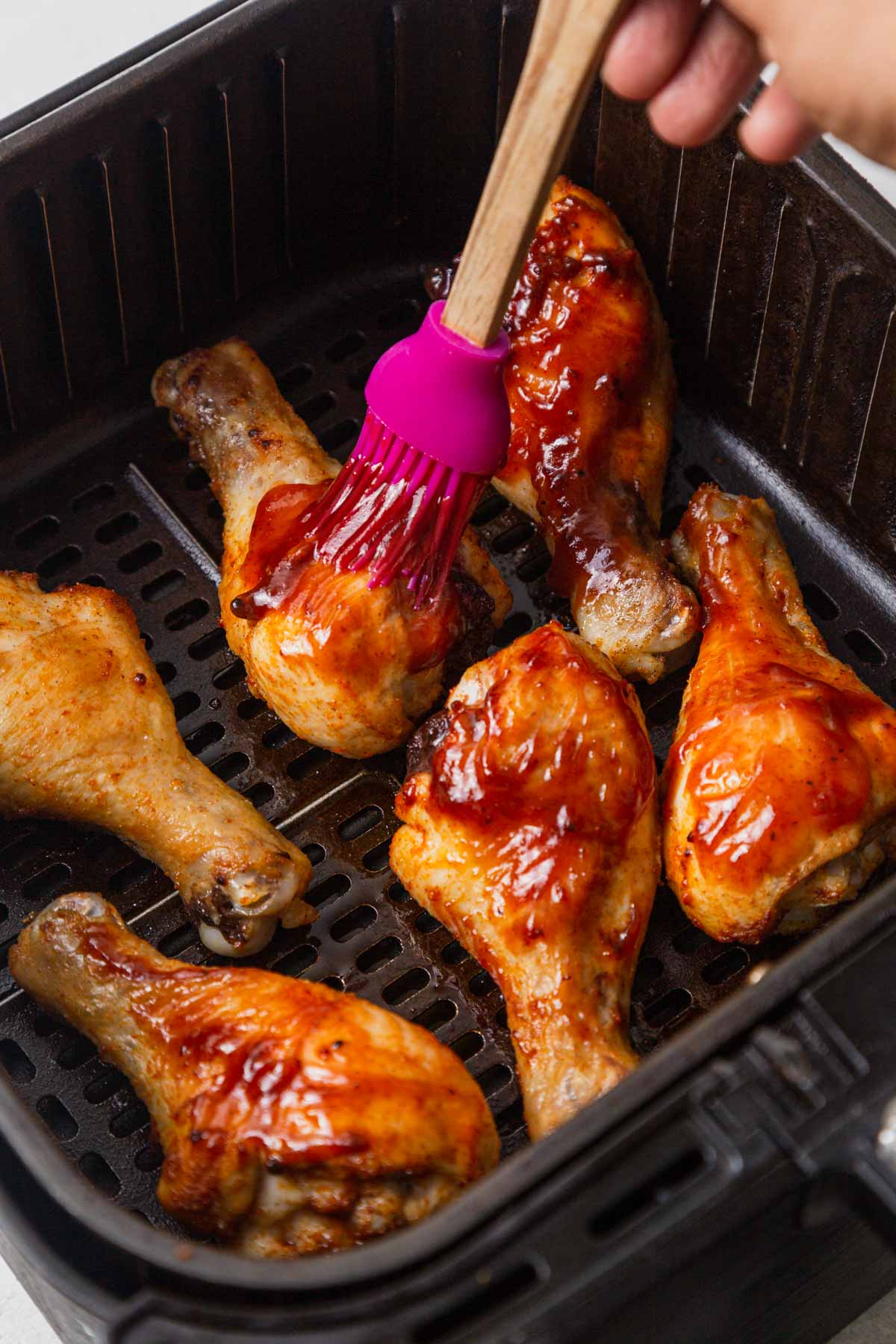 brushing bbq sauce onto the chicken legs.