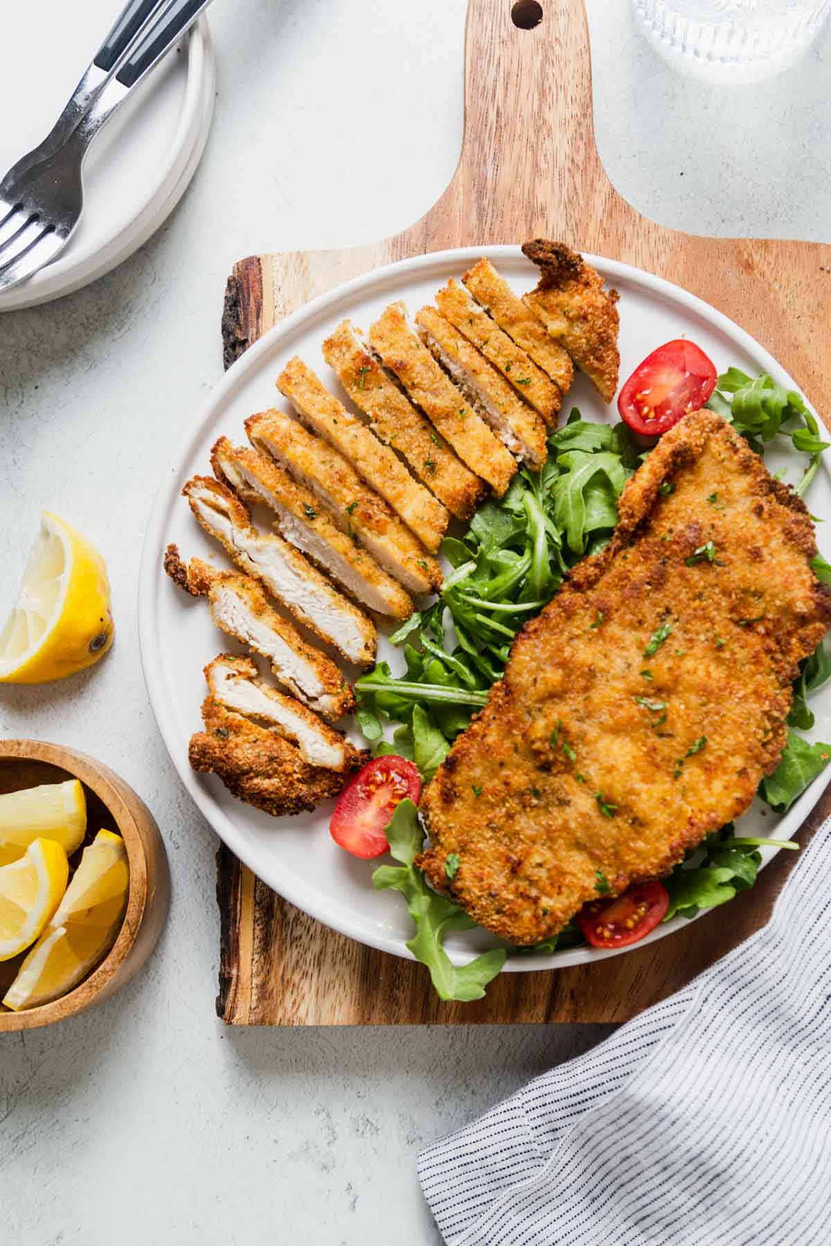 air fryer chicken cutlets sliced and on a white plate with a salad.