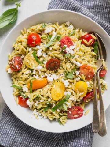 pesto orzo salad on a bowl with a spoon.