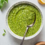 pesto in a bowl with a spoon on a white table.