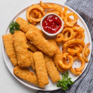 air fried frozen fish sticks on a plate with ketchup and fries.
