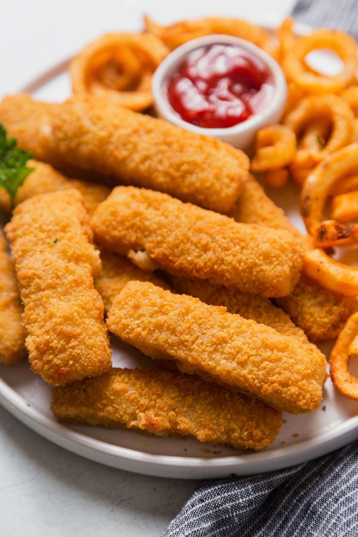 fish sticks in the air fryer on a plate with sauce.