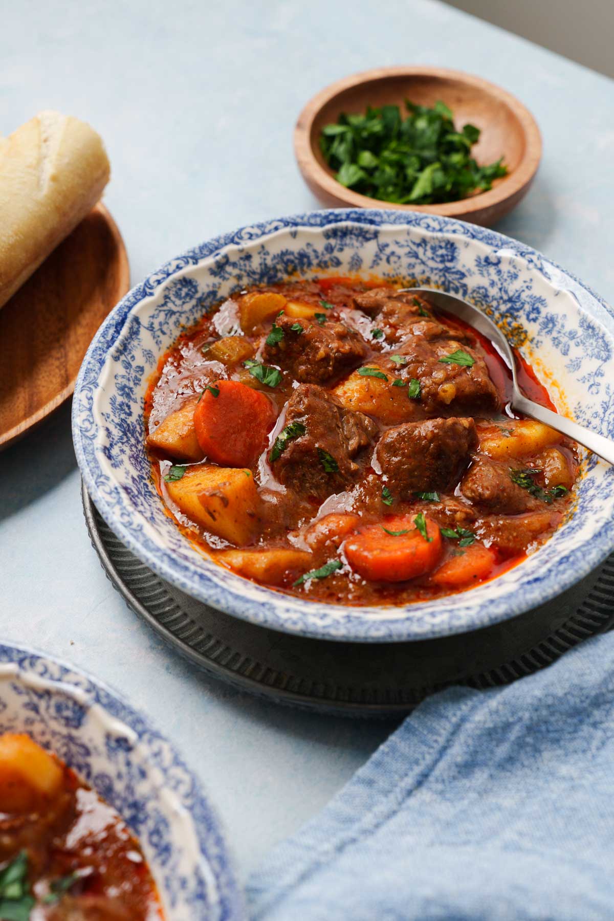 spicy beef stew in a bowl with bread on the side.
