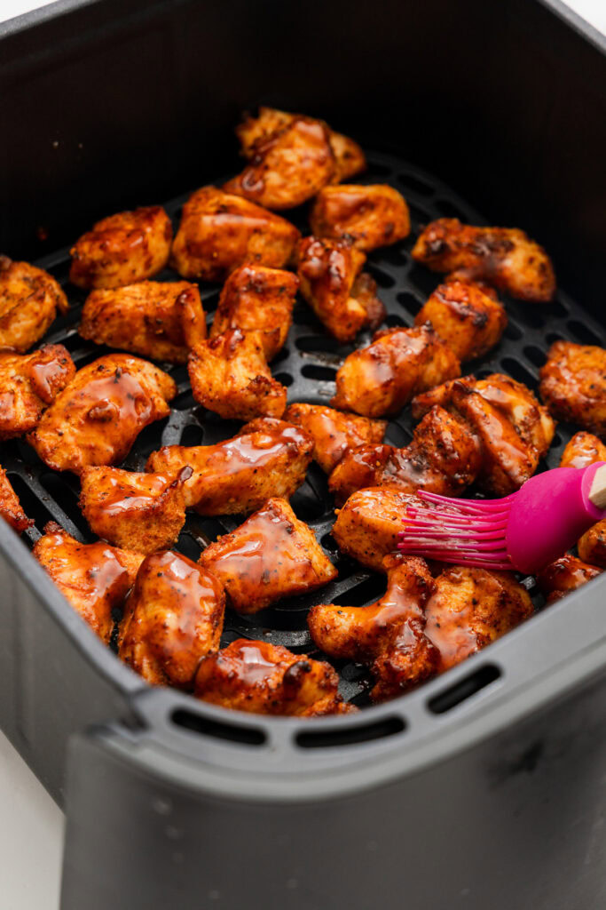 brushing bbq sauce to the chicken bites.