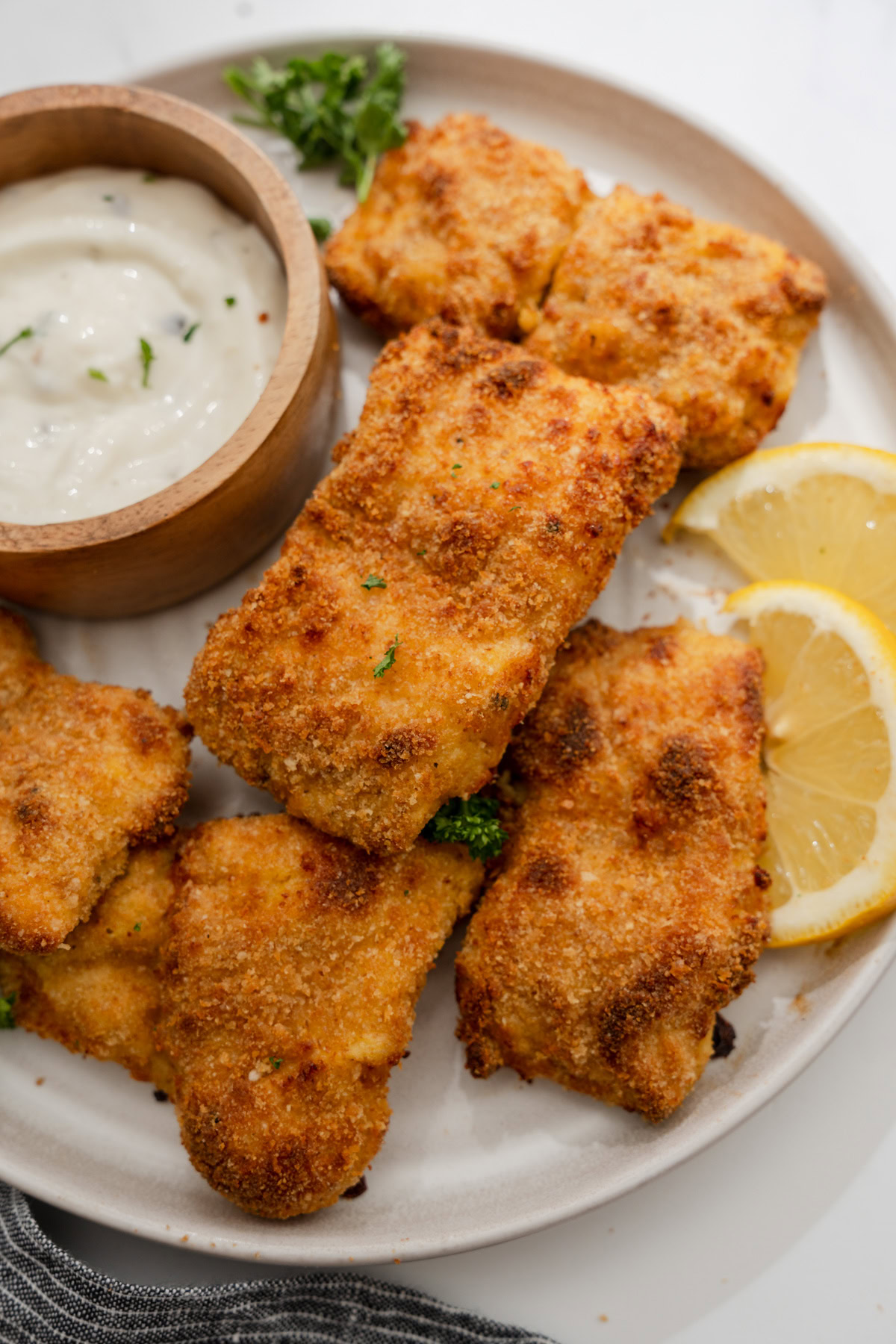 air fryer fried fish on a plate with tartar sauce.