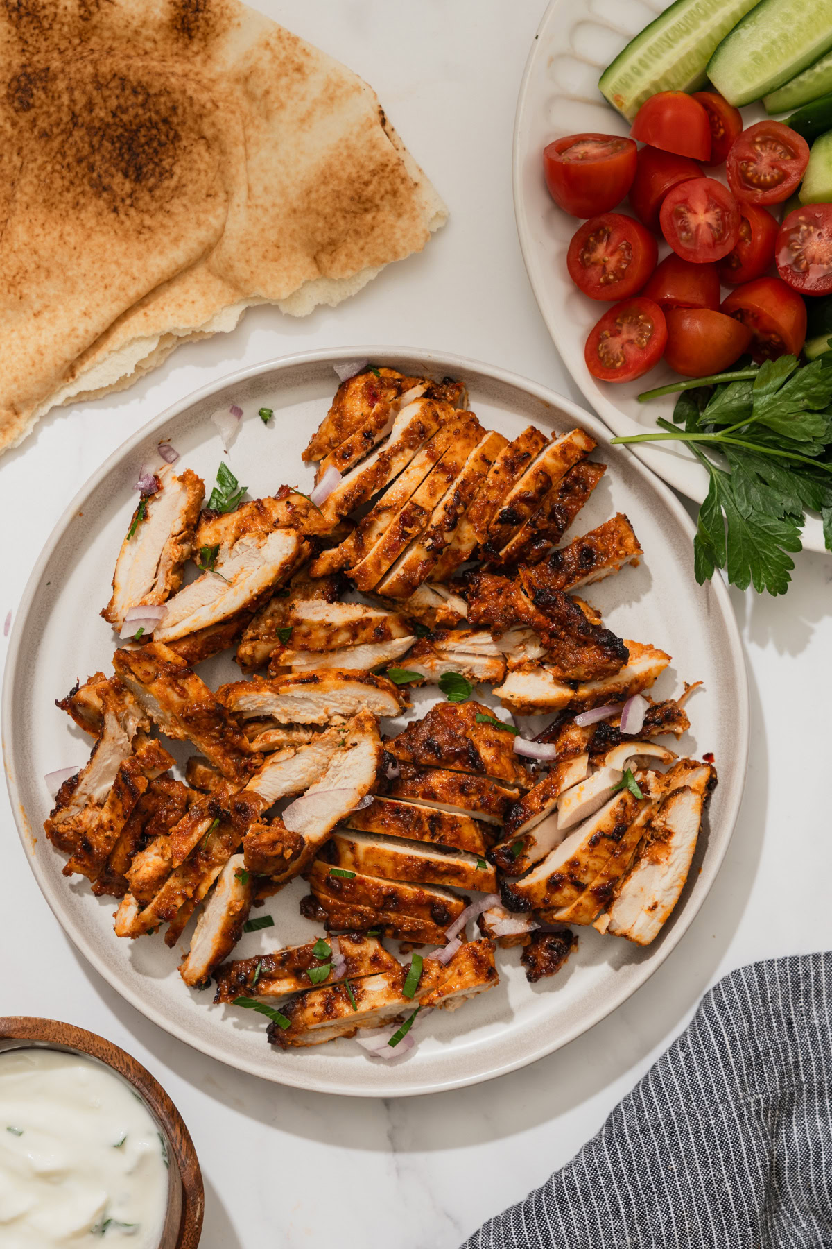 air fryer harissa chicken sliced on a plate along with pita bread.