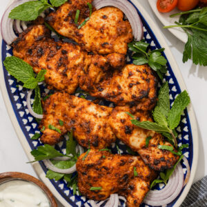 air fryer harissa chicken on a platter with yogurt on the side.