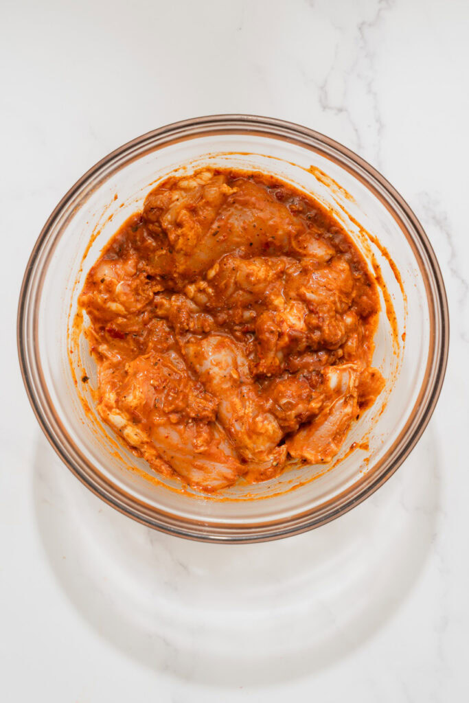 chicken coated in harissa marinade in a bowl.