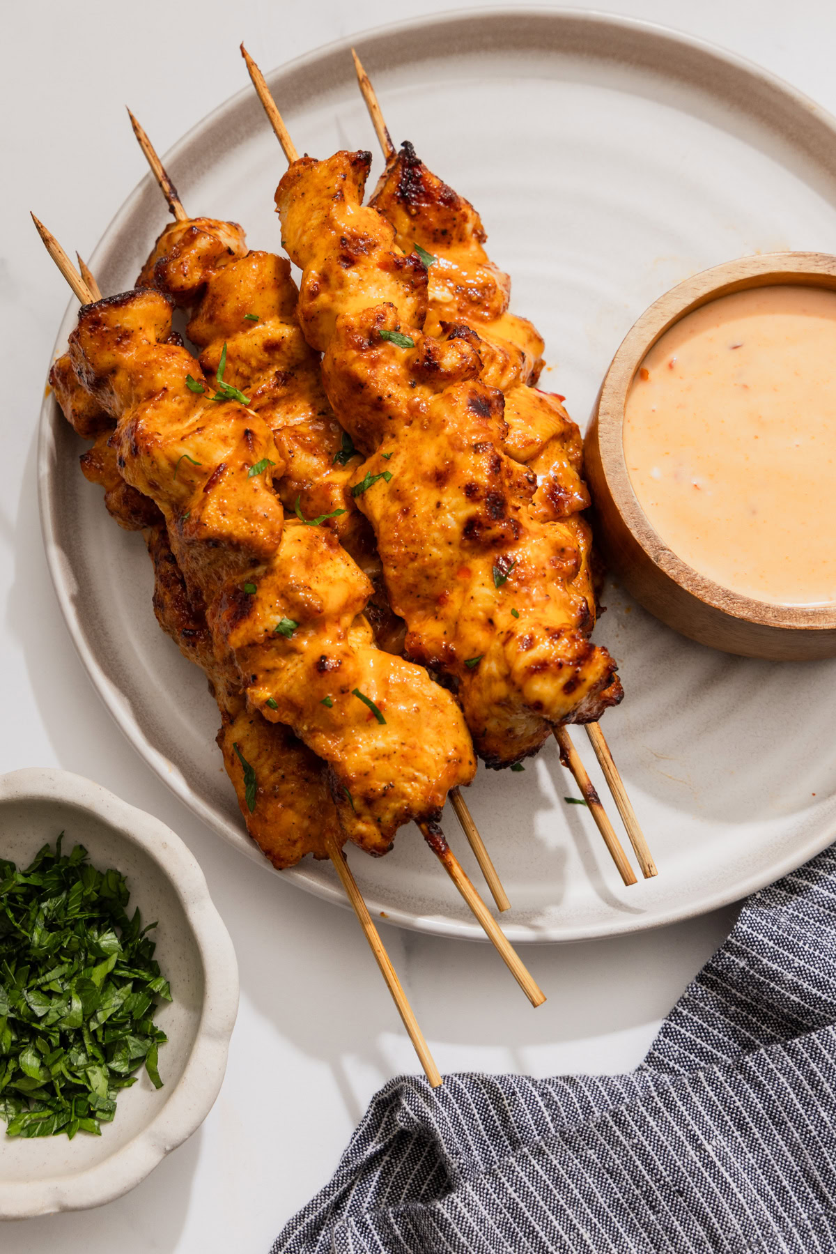 air fryer bang bang chicken on a plate with bang bang sauce on the side on a white background.