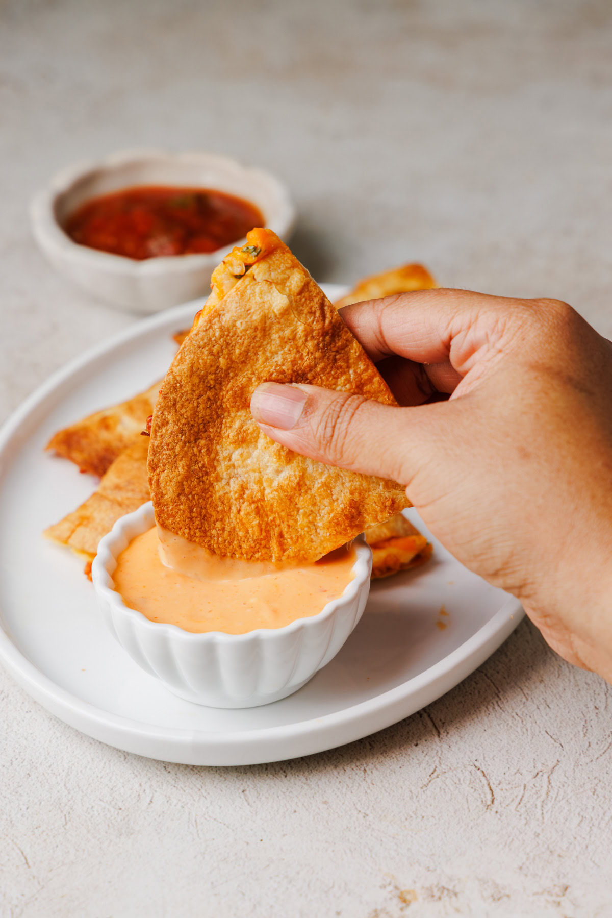 air fryer quesadilla being dipped in spicy mayo sauce.