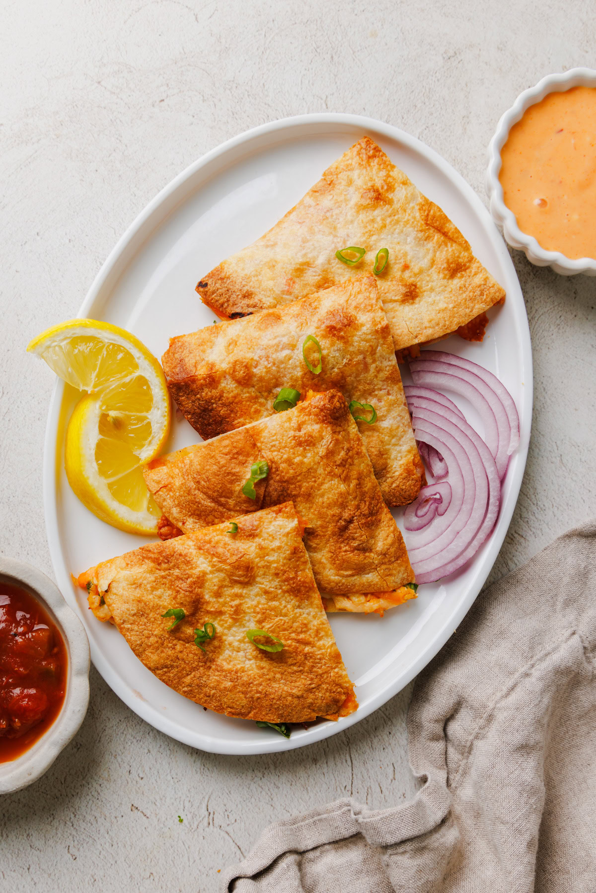 Air fryer chicken quesadillas on a white plate with salsa on the side.