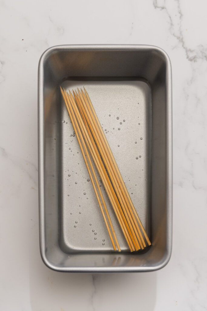 bamboo skewers soaking in a loaf pan.