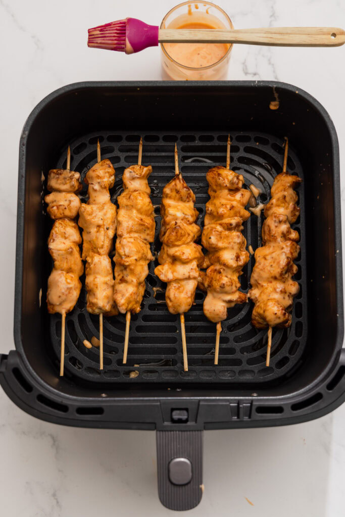 brushing bang bang sauce on the air fried chicken.