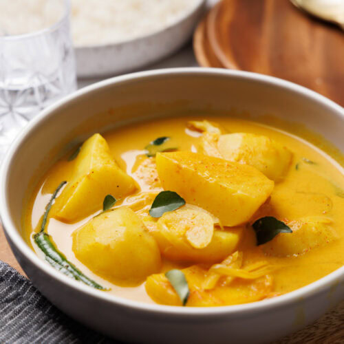 sri lankan potato curry on a bowl with rice on the side.