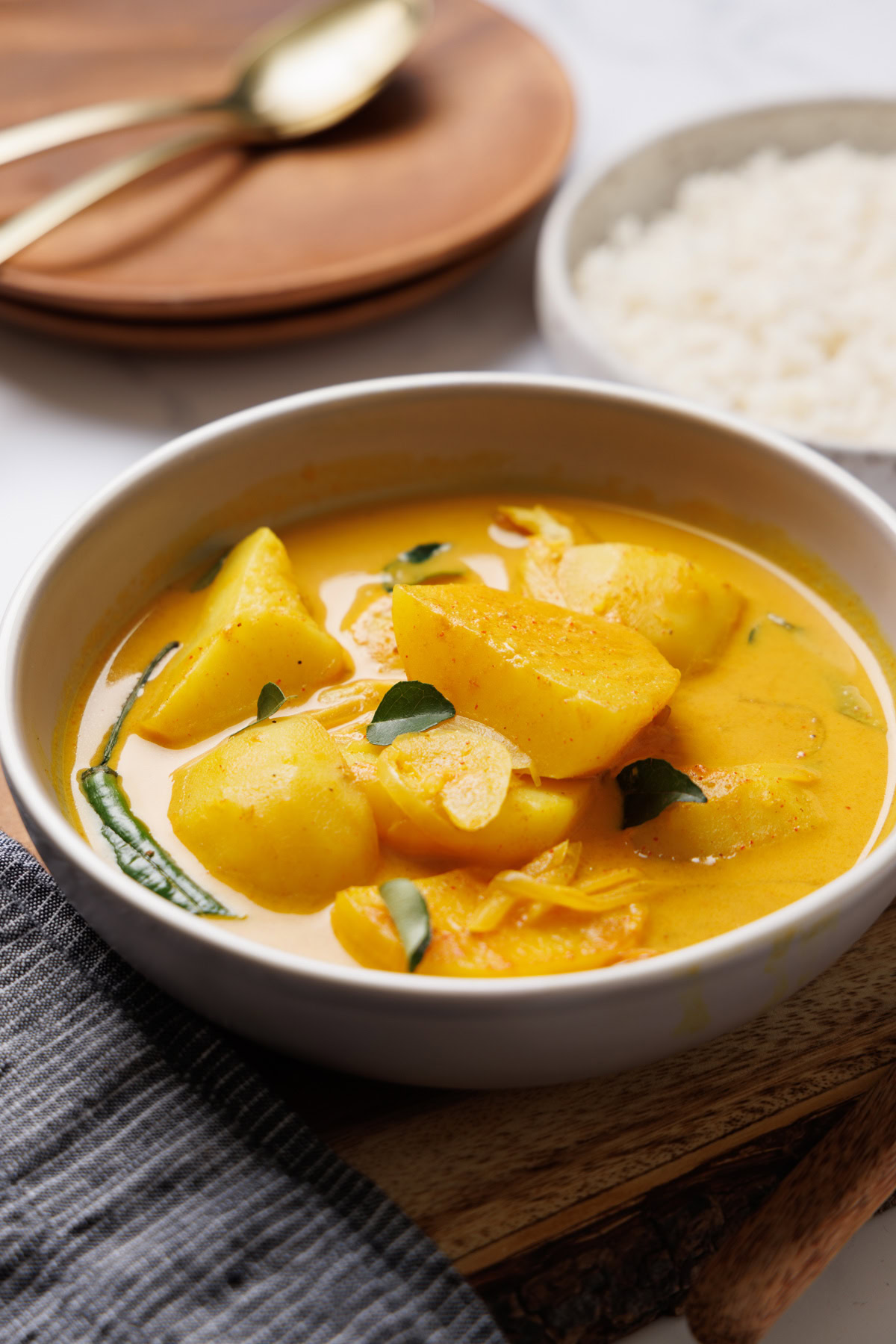 Potato curry in a rich, flavorful yellow coconut milk sauce, served with rice, highlighting authenti.